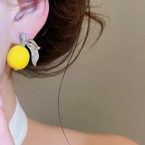 Orecchini a perno a limone con zirconi su modella, design di gioielli alla frutta estiva