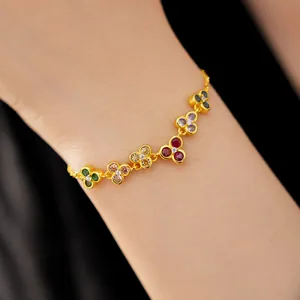 Close-up of elegant gold bracelet with multi-colored zircon flower motifs on wrist