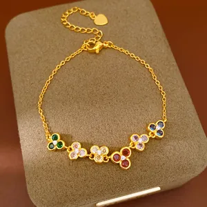 Detail view of a gold chain bracelet with vibrant colorful zircon flower charms.