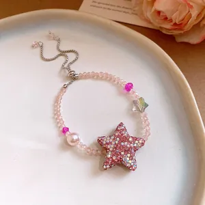 Gros plan d'un bracelet en perles roses avec une étoile en zircon et une perle