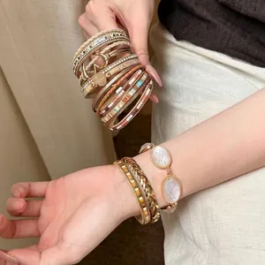 Dettaglio di bracciali in pelle multistrato boho con cuore in resina e dettagli intrecciati.