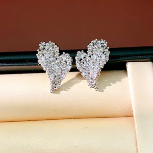 Gros plan de boucles d'oreilles cœurs étincelantes avec pavé de zircones sur support