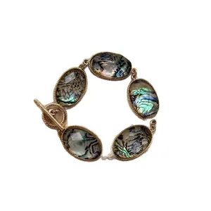 Bracciale bohémien dorato con pietre ovali in resina stile abalone e chiusura T