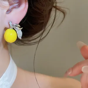 Primo piano di un vivace orecchino a limone giallo con foglie di zircone sull'orecchio