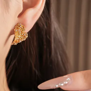 Gros plan détaillé montrant une boucle d'oreille en forme de cœur dorée avec zircone