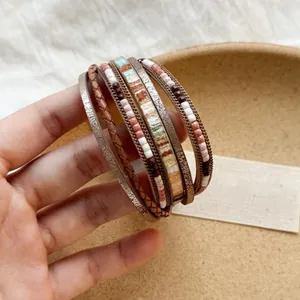 Dettaglio macro di un bracciale boho multistrato in pelle con vivaci perline etniche
