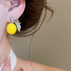 Primo piano di uno squisito orecchino a limone con micro-pavé di zirconi per uno stile estivo