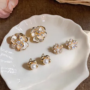 Close-up of three pairs of French vintage flower stud earrings displayed on a white shell plate