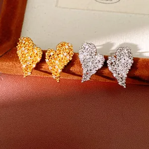 Gros plan de boucles d'oreilles cœur texturées avec zircons en doré et argenté