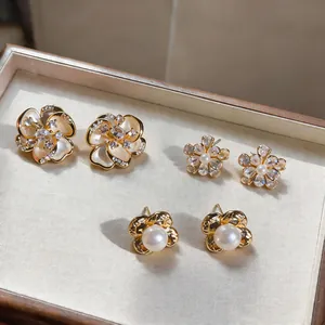 Close-up of three pairs of vintage pearl and zircon flower stud earrings in a display tray