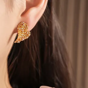 Vue rapprochée de boucles d'oreilles cœur plaquées or 18 carats portées sur l'oreille