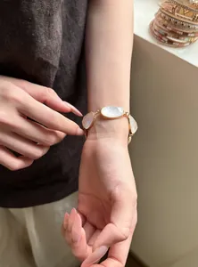 Dettaglio di un bracciale vintage dorato con pietre ovali bianche indossato su un polso