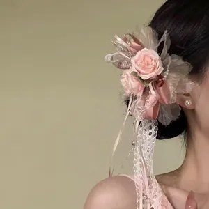 Exquisites Detail einer rosa Rosen-Haarklammer mit zarten Spitzenbändern und Perlen