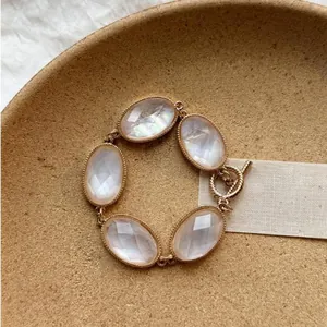 Vista dettagliata di un bracciale bohémien dorato con pietre ovali in resina e chiusura a T