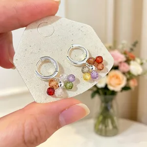 Close-up of silver hoop earrings with colorful candy-colored glass beaded charms in detail.