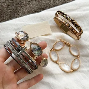 Vista dettagliata di bracciali bohémien in pelle multistrato con strass e ciondolo a croce