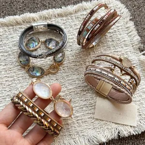 Dettaglio di bracciali boho multistrato in pelle con accenti in resina e cristalli
