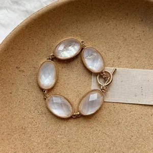 Dettaglio di un bracciale dorato bohémien con cinque pietre di resina ovali sfaccettate.