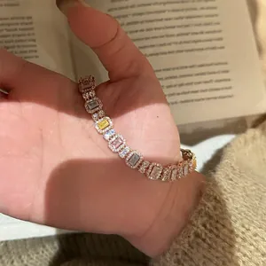 Nahaufnahme eines eleganten Zirkonia-Armbands mit quadratischen Steinen vor einem Buchhintergrund.