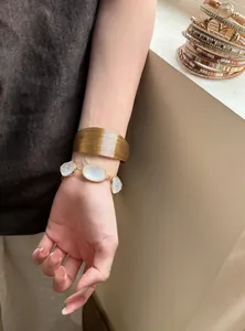 Braccialetti bohémien multistrato in pelle e resina dorata presentati su un polso femminile.