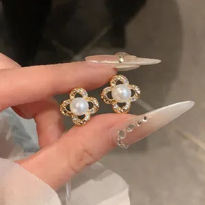 Detailed view of elegant gold-tone flower stud earrings with pearl and sparkling zircon