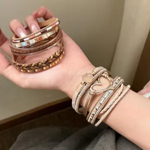 Dettaglio di bracciale bohémien multistrato in pelle con cuore in strass lucido