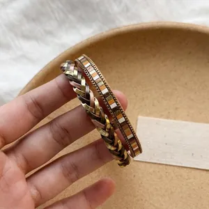Dettaglio di bracciali bohémien in pelle intrecciata e motivi geometrici da donna