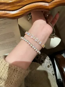 Nahaufnahme von elegantem Zirkon-Armband und Perlenkette am Handgelenk
