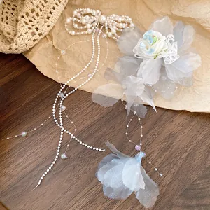 Detailed view of elegant pearl bow tassel and grey fabric flower hair clips