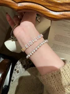 Nahaufnahme von roségoldenem Zirkonia-Armband und Perlenarmband im Schicht-Look
