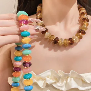 Detail view of colorful and amber acrylic beaded necklaces on a model's neck
