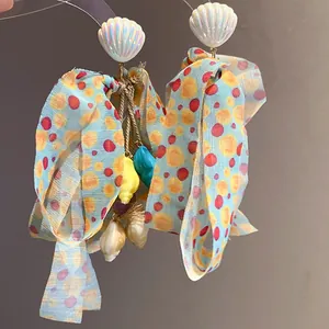 Exquisite close-up of beach-themed earrings with polka dot bows and iridescent shells