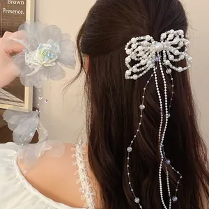 Detail view of an elegant pearl bow hair clip with tassels and a floral hair accessory.