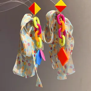 Close-up of colorful mismatched drop earrings with plastic chains and polka dot ribbons