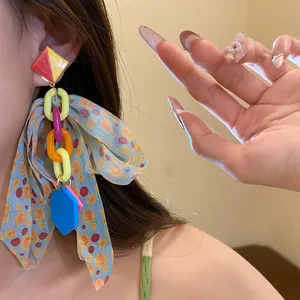 Detailed shot of colorful oversized bow earrings with geometric chain links on model