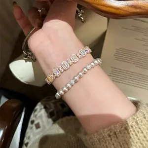 Detailansicht eines eleganten Armbands mit Zirkonia-Gliedern und einer Perlenkette am Handgelenk