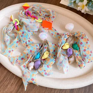 Detailed close-up of summer vacation style earrings with seashell charms and polka dot bows