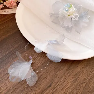 Detailed view of a light blue organza flower hair clip with pearl tassels.