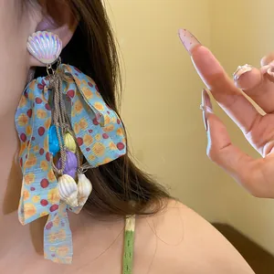 Detailed macro view of colorful shell tassel bow earrings with a tropical vacation vibe