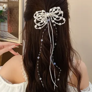 Detailed view of an elegant pearl bow hair clip with long hanging pearl tassels.