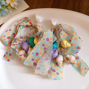 Macro view of shell and conch tassel earrings with light blue polka dot ribbon bows