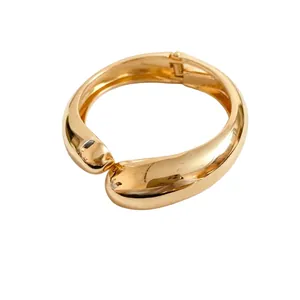 Bracciale rigido dorato lucido con design a goccia incrociata in stile minimalista retrò