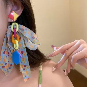 Detail of model wearing colorful bohemian bow tassel earrings with resin chain links