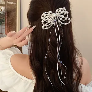 Close-up view of a sweet pearl bow hair clip with long tassels on wavy brown hair.