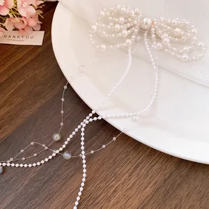 Detail view of a white pearl bow hair clip with elegant long tassels on a plate