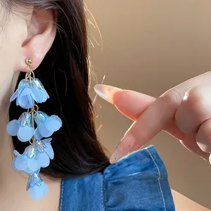 Detailed macro view showing light blue chiffon flower tassel earrings worn by an Asian model