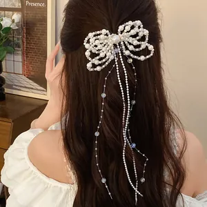Detailed view of elegant pearl bow hair clip with long sparkling tassels