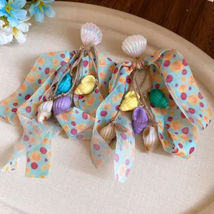 Close-up of beach-themed earrings with shell charms and colorful bow tassels