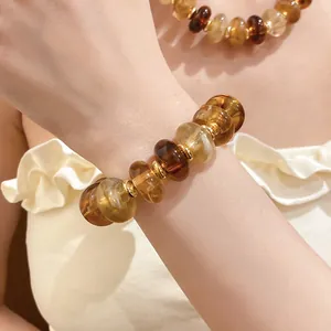 Detailed macro view of marbled amber acrylic bead bracelet with golden metallic spacers