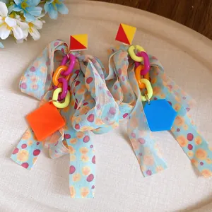 Close-up of vibrant chiffon bow tassel earrings with geometric plastic pendants